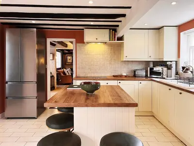 a kitchen with white cabinets and a wooden counter top at Peak Hill Cottage in Theberton