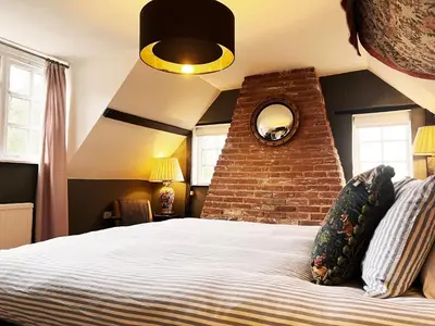 a bedroom with a bed with a brick wall at Peak Hill Cottage in Theberton