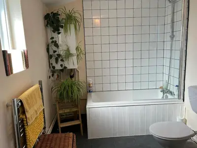 a bathroom with a tub and a toilet and plants at Quiet getaway for 2 near Bury St Edmunds in Honington