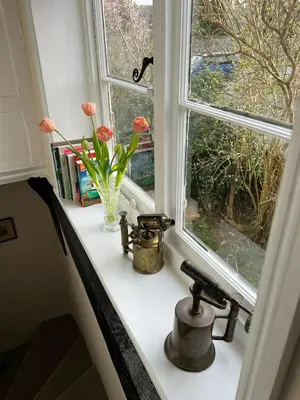 a window with flowers in a vase on a counter at Quiet getaway for 2 near Bury St Edmunds in Honington