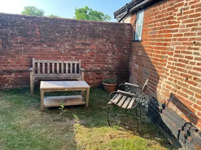 a bench and a table next to a brick wall at Quiet getaway for 2 near Bury St Edmunds in Honington