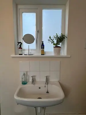 a bathroom sink with a mirror and a window at Quiet getaway for 2 near Bury St Edmunds in Honington