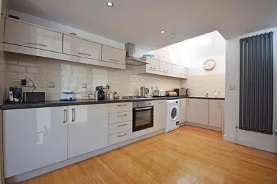 a large kitchen with white cabinets and a window at Beautiful flat in a perfect location in Cambridge