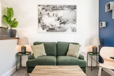 a living room with a green couch and a painting at Superb 2BR 2Bath with parking in Saxmundham
