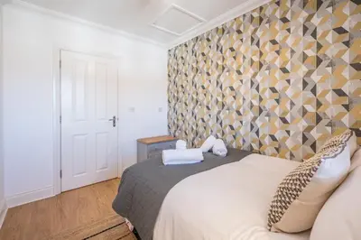 a bedroom with a bed with a geometric wall at Superb 2BR 2Bath with parking in Saxmundham