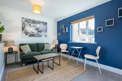 a living room with a green couch and a blue wall at Superb 2BR 2Bath with parking in Saxmundham