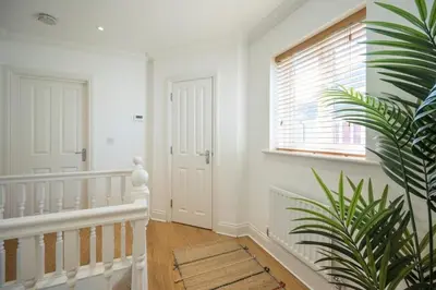 a white hallway with a staircase and a window at Superb 2BR 2Bath with parking in Saxmundham