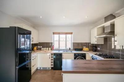 a kitchen with white cabinets and a black refrigerator at Superb 2BR 2Bath with parking in Saxmundham