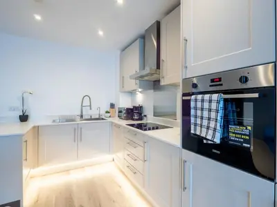 a kitchen with white cabinets and a black appliance at Cosy 2-Bed Next to Harlow Town in Harlow