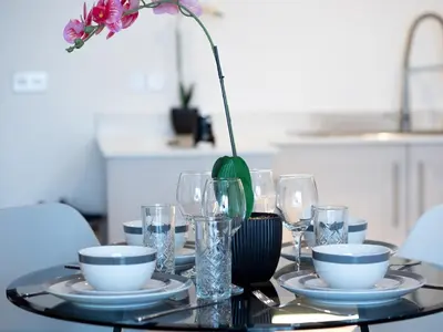 a table with plates and glasses and a vase with a flower at Cosy 2-Bed Next to Harlow Town in Harlow