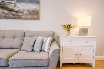 a living room with a couch and a table with a lamp at North Cottage, Aldeburgh in Aldeburgh
