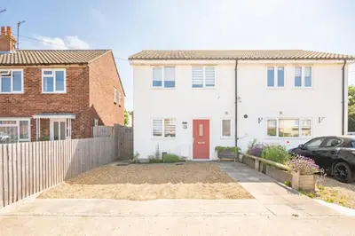 a white house with a red door and a fence at Modern 2-Bed Home in Leiston in Leiston