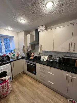 a kitchen with white cabinets and black counter tops at Aneliya home in Enfield