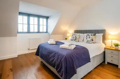 a bedroom with a large bed with towels on it at 4 Oakes Court, Thorpeness - Sleeps 6 - Close to Thorpeness Meare and the beach, Close to Thorpeness Golf, Hotel and Country Club, Only 2 miles from #Aldeburgh, Managed by Aldeburgh Coastal Cottages in Thorpeness