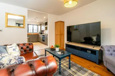 a living room with a couch and a large flat screen tv at 4 Oakes Court, Thorpeness - Sleeps 6 - Close to Thorpeness Meare and the beach, Close to Thorpeness Golf, Hotel and Country Club, Only 2 miles from #Aldeburgh, Managed by Aldeburgh Coastal Cottages in Thorpeness