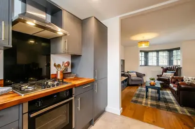 a kitchen with stainless steel appliances and a living room at 4 Oakes Court, Thorpeness - Sleeps 6 - Close to Thorpeness Meare and the beach, Close to Thorpeness Golf, Hotel and Country Club, Only 2 miles from #Aldeburgh, Managed by Aldeburgh Coastal Cottages in Thorpeness