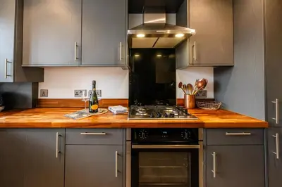 a kitchen with gray cabinets and a wooden counter top at 4 Oakes Court, Thorpeness - Sleeps 6 - Close to Thorpeness Meare and the beach, Close to Thorpeness Golf, Hotel and Country Club, Only 2 miles from #Aldeburgh, Managed by Aldeburgh Coastal Cottages in Thorpeness