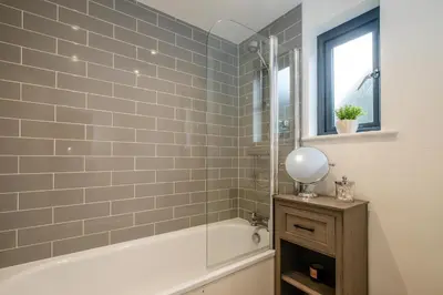 a bathroom with a tub and a shower with a mirror at 4 Oakes Court, Thorpeness - Sleeps 6 - Close to Thorpeness Meare and the beach, Close to Thorpeness Golf, Hotel and Country Club, Only 2 miles from #Aldeburgh, Managed by Aldeburgh Coastal Cottages in Thorpeness