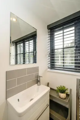 a bathroom with a white sink and a mirror at 4 Oakes Court, Thorpeness - Sleeps 6 - Close to Thorpeness Meare and the beach, Close to Thorpeness Golf, Hotel and Country Club, Only 2 miles from #Aldeburgh, Managed by Aldeburgh Coastal Cottages in Thorpeness