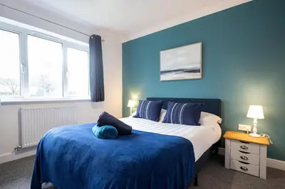 a bedroom with blue walls and a bed with a blue blanket at Shrub End Lodge - Colchester in Lexden