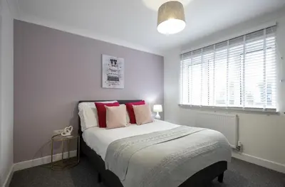 a bedroom with a large bed with red pillows at Shrub End Lodge - Colchester in Lexden