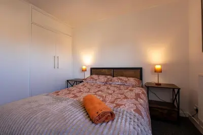 a bedroom with a bed with an orange blanket on it at Sizewell - Lincoln - Contractor Accommodation in Saxmundham