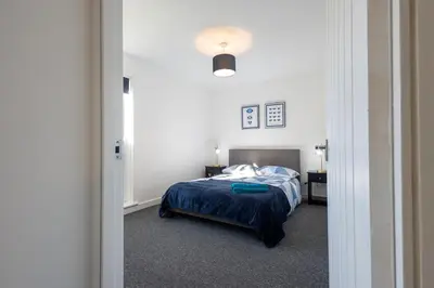a bedroom with a bed with a blue blanket at Sizewell - Lincoln - Contractor Accommodation in Saxmundham