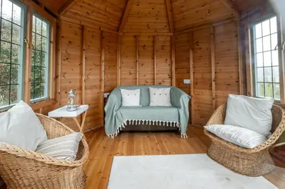 a living room with wicker chairs and a couch at Heronsmead, sleeps 8 - Large Thorpeness house on the banks of Thorpness Meare - a boating lake - Close to Thorpeness beach, Golf Club and Thorpeness Country Club - Aldeburgh Coastal Cottages in Thorpeness