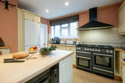 a kitchen with a stove and a bowl of fruit on the counter at Heronsmead, sleeps 8 - Large Thorpeness house on the banks of Thorpness Meare - a boating lake - Close to Thorpeness beach, Golf Club and Thorpeness Country Club - Aldeburgh Coastal Cottages in Thorpeness