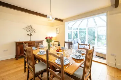 a dining room with a wooden table and chairs at Heronsmead, sleeps 8 - Large Thorpeness house on the banks of Thorpness Meare - a boating lake - Close to Thorpeness beach, Golf Club and Thorpeness Country Club - Aldeburgh Coastal Cottages in Thorpeness