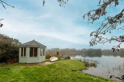a small shed on the side of a lake at Heronsmead, sleeps 8 - Large Thorpeness house on the banks of Thorpness Meare - a boating lake - Close to Thorpeness beach, Golf Club and Thorpeness Country Club - Aldeburgh Coastal Cottages in Thorpeness