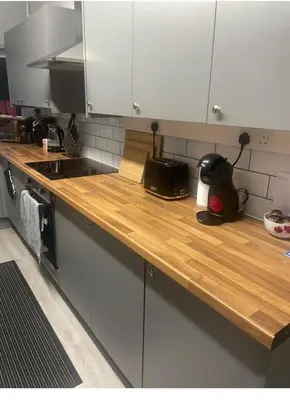 a kitchen with white cabinets and a wooden counter top at Leiston house in Leiston