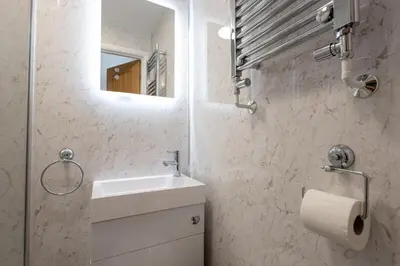 a white bathroom with a sink and a mirror at Sizewell - Contractor Accommodation in Leiston