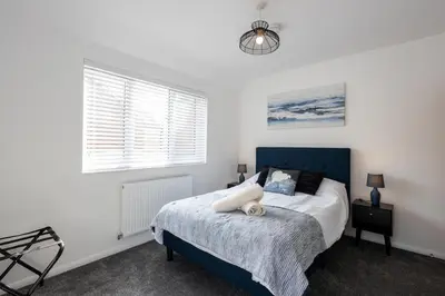 a bedroom with a bed with a blue headboard and a window at Sizewell - Contractor Accommodation in Leiston