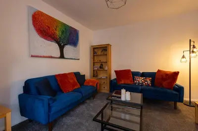 a living room with two blue couches and a painting at Sizewell - Contractor Accommodation in Leiston