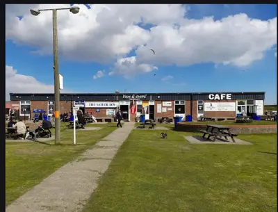a building with people sitting in a park at Tracis home from home in Jaywick Sands