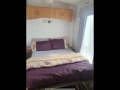 a small bedroom with a bed with purple sheets at Tracis home from home in Jaywick Sands