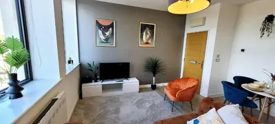 a living room with a television and a table and chairs at Stylish 2 Bedroom Flat near Chelmsford Station, with Free Parking, Sleeps 4 in Chelmsford