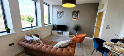 a living room with a couch and a table at Stylish 2 Bedroom Flat near Chelmsford Station, with Free Parking, Sleeps 4 in Chelmsford