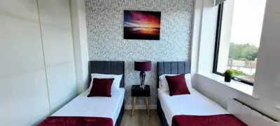 two beds in a room with two windows at Stylish 2 Bedroom Flat near Chelmsford Station, with Free Parking, Sleeps 4 in Chelmsford