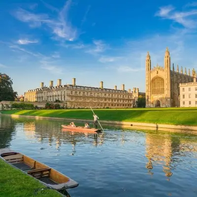 two people in a boat on a river in front of a building at Cosy Rural Retreat Perfect for Families and Pets in Tuddenham