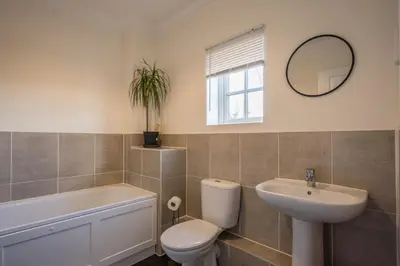 a bathroom with a toilet and a sink and a mirror at Comfortable 2-Bedroom Home in Framlingham in Framlingham