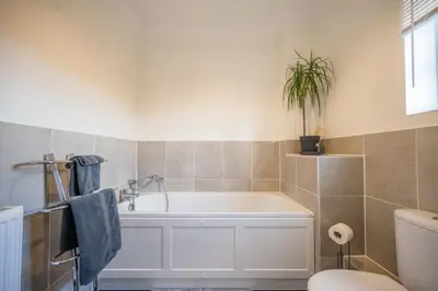 a bathroom with a tub and a toilet and a plant at Comfortable 2-Bedroom Home in Framlingham in Framlingham