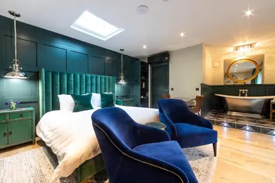 a bedroom with a bed and two blue chairs at Eagle Mill Luxury Rooms in Huntingdon