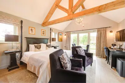 a bedroom with a bed and two chairs and a desk at Eagle Mill Luxury Rooms in Huntingdon