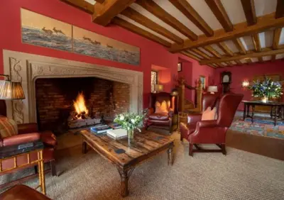 a living room with a fireplace and red walls at The Old Hall Ely in Ely