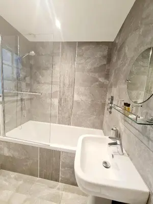 a bathroom with a sink and a shower and a tub at The Harvard Inn in Stock