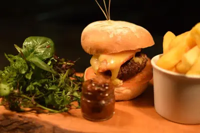 a cheeseburger and french fries on a wooden table at The Dolphin Inn in Thorpeness