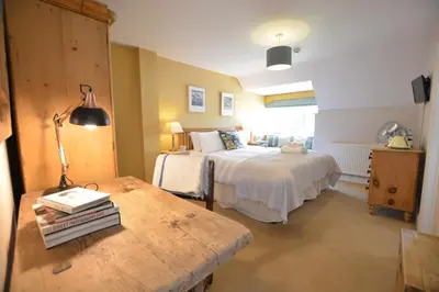 a bedroom with two beds and a table with a lamp at The Dolphin Inn in Thorpeness