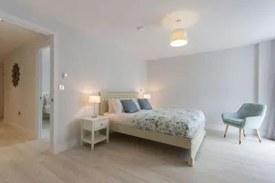 a white bedroom with a bed and a chair at Citystay Living - Vesta Apartments in Cambridge